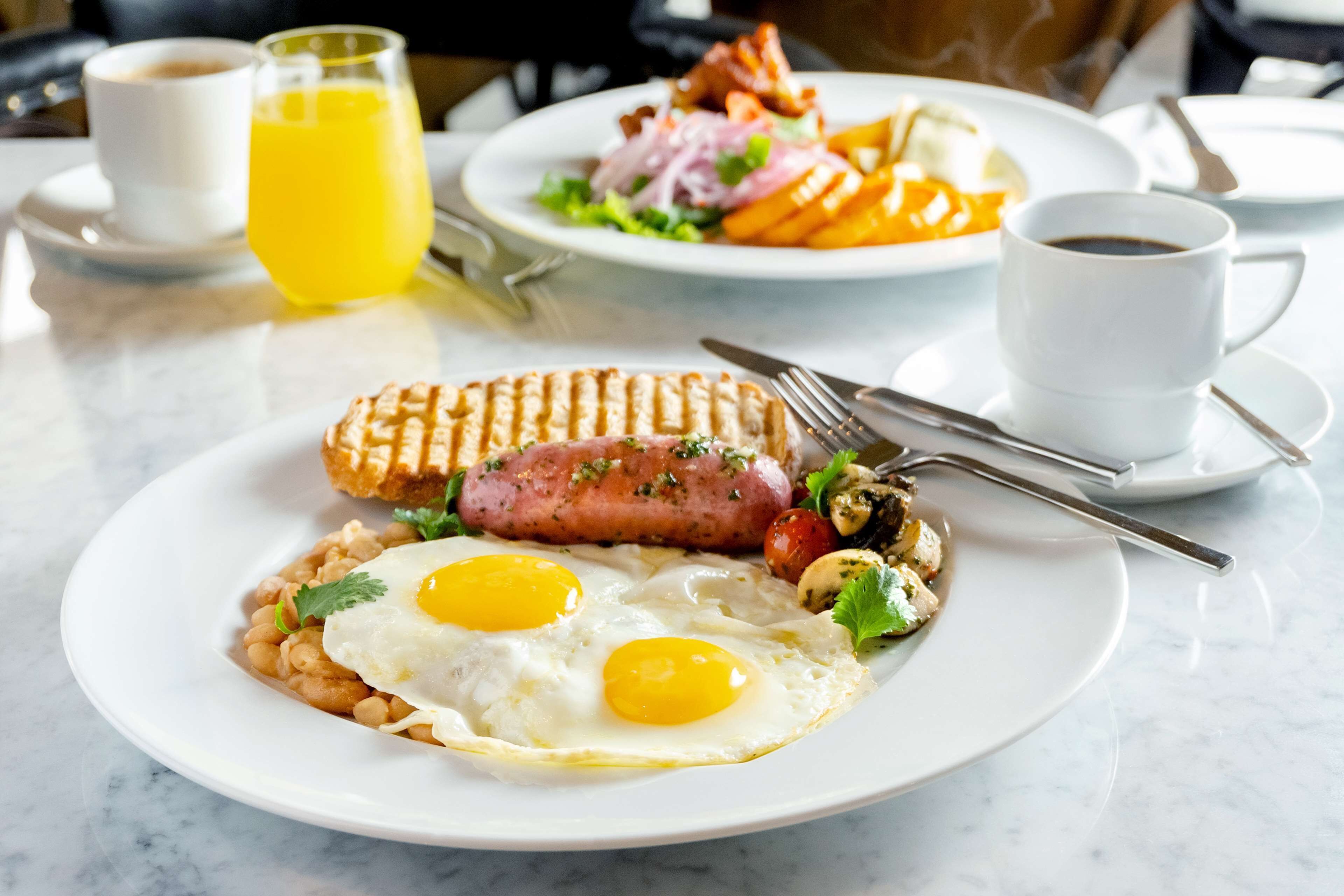 A breakfast plate with eggs, sausage, beans, and mushrooms.