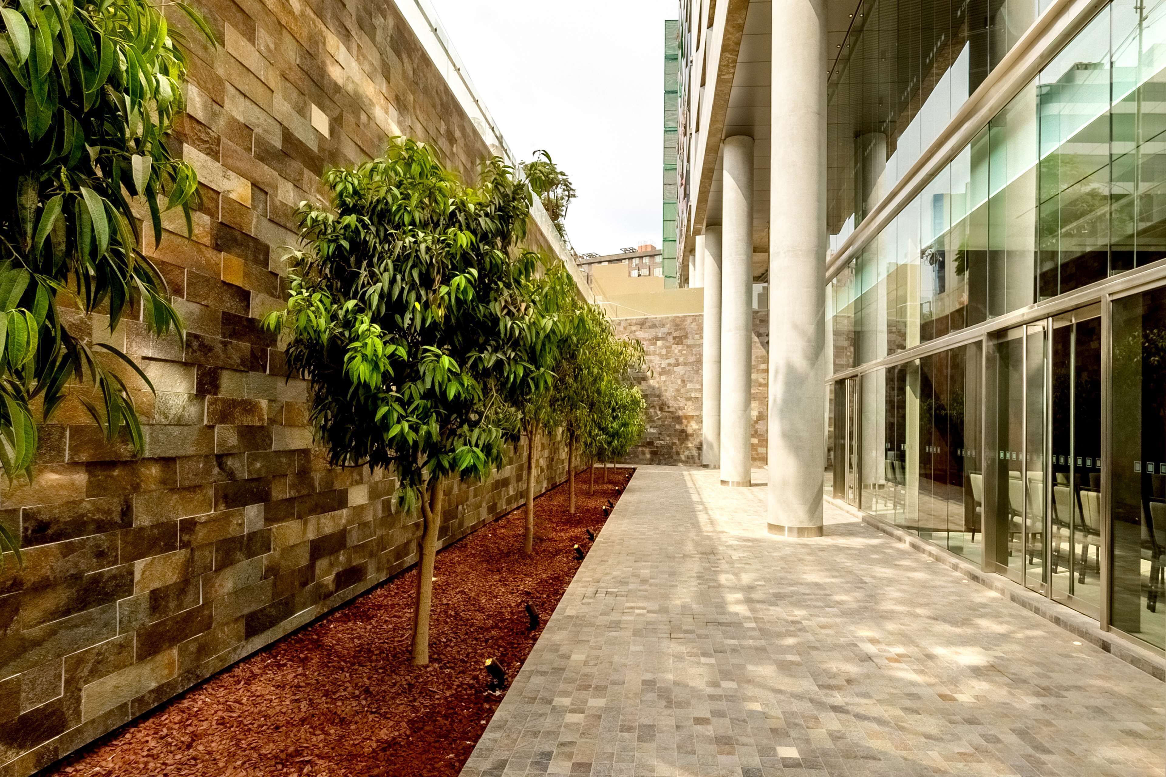 A corridor with a brick wall on one side and a glass building on the other.
