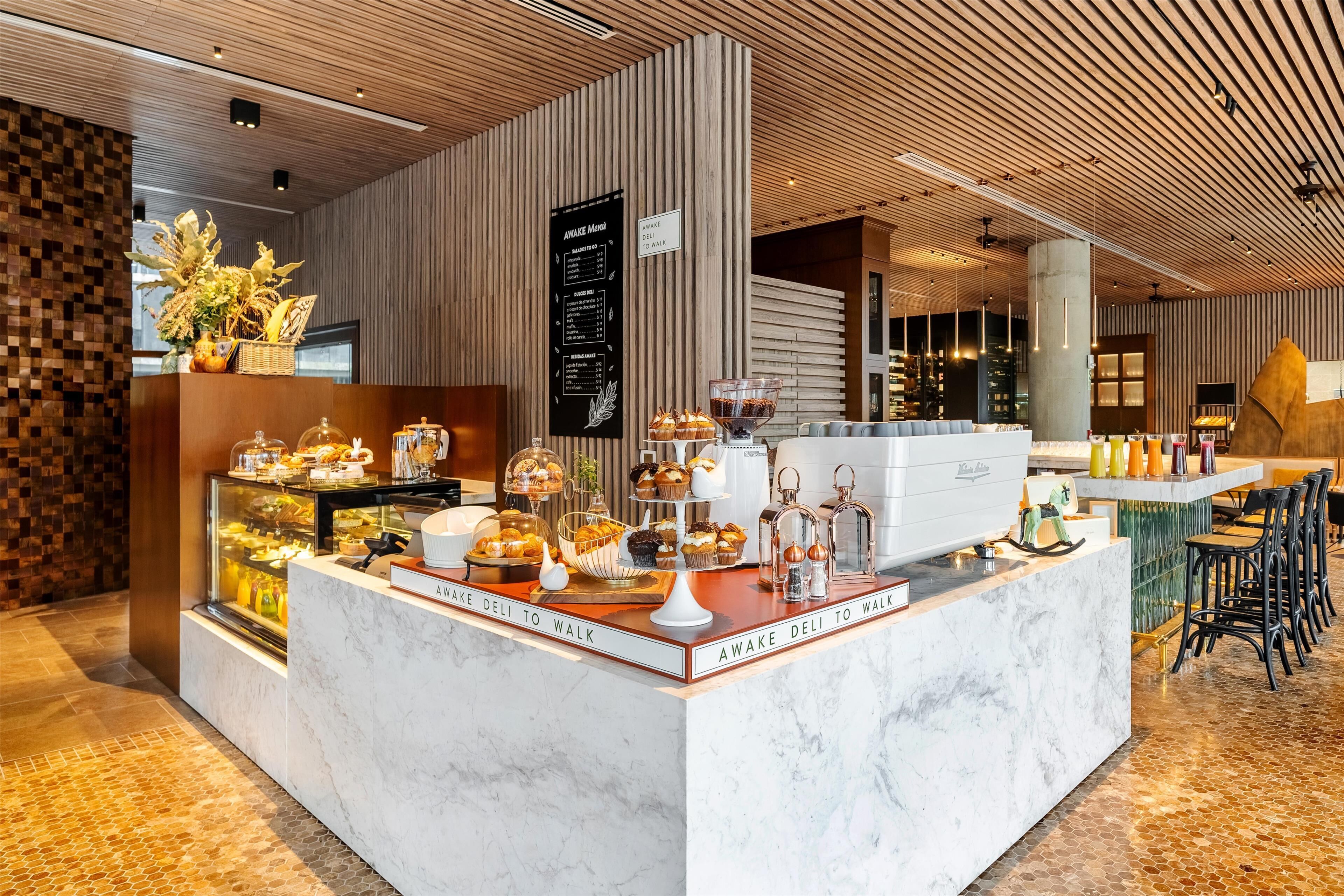 A modern cafe with a marble counter displaying pastries and a menu board.