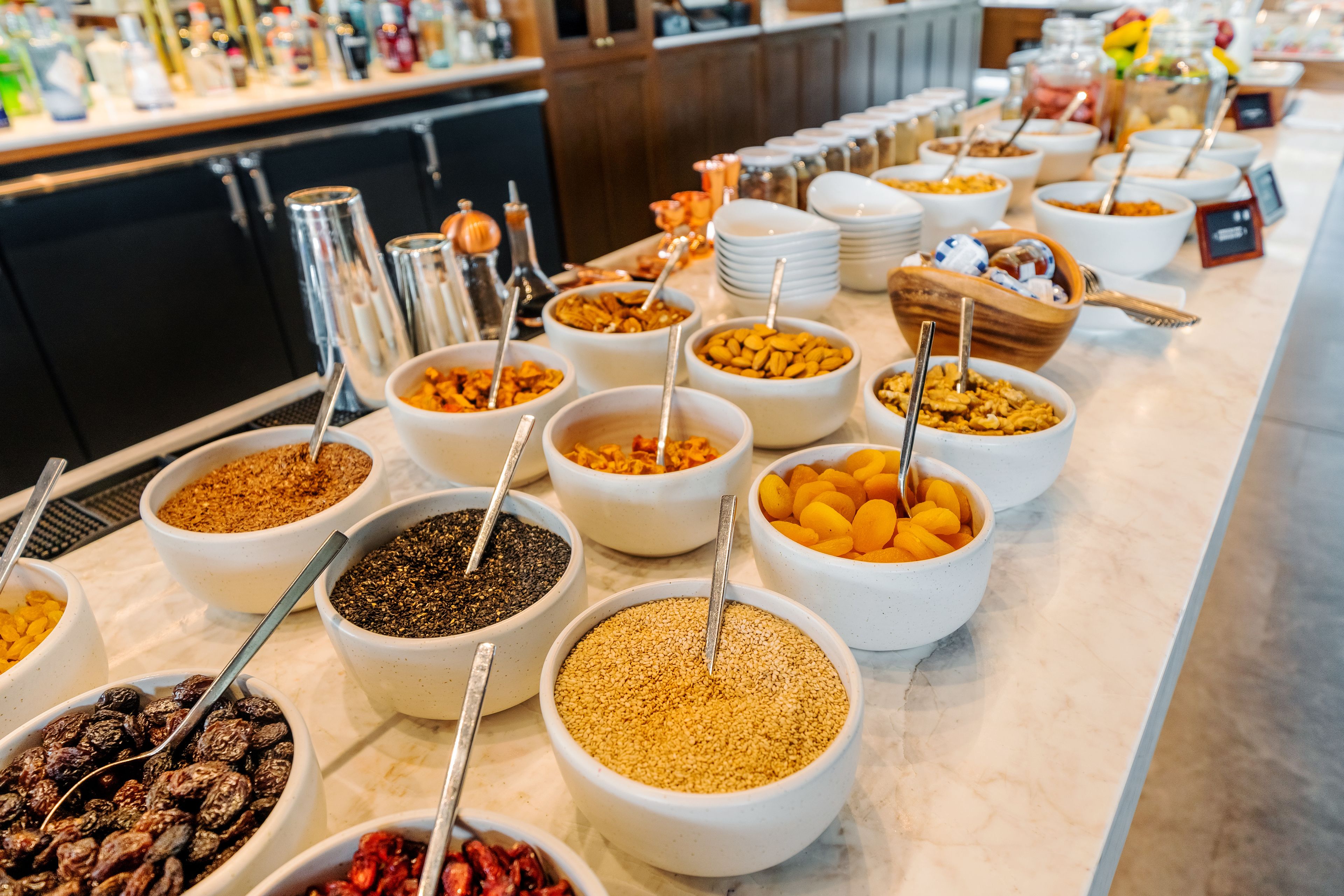 A buffet with various food items in bowls, including nuts, dried fruits, and grains.