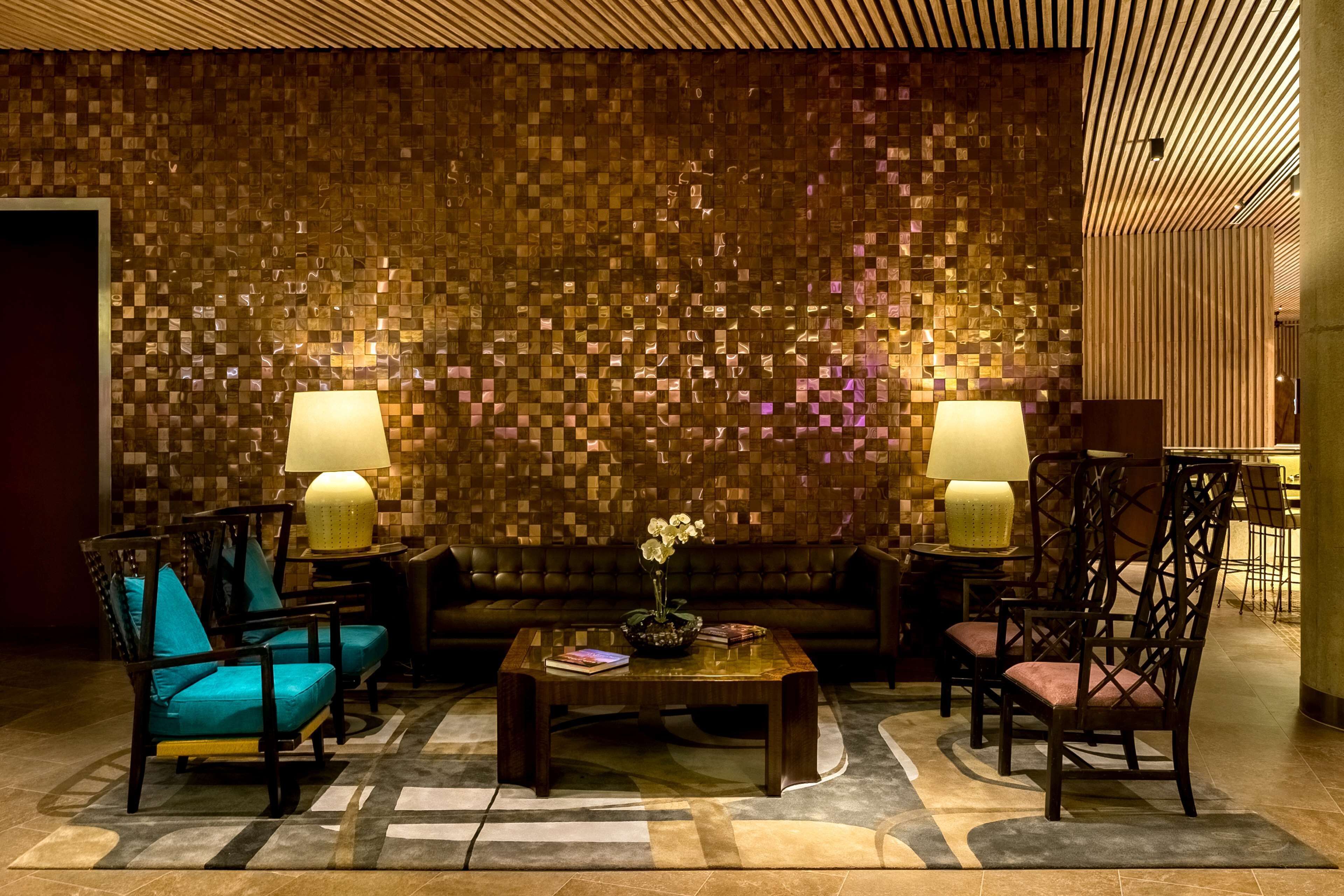 Un hall d’entrée avec un mur décoré de mosaïques, un canapé, deux fauteuils, une table basse et deux lampes.