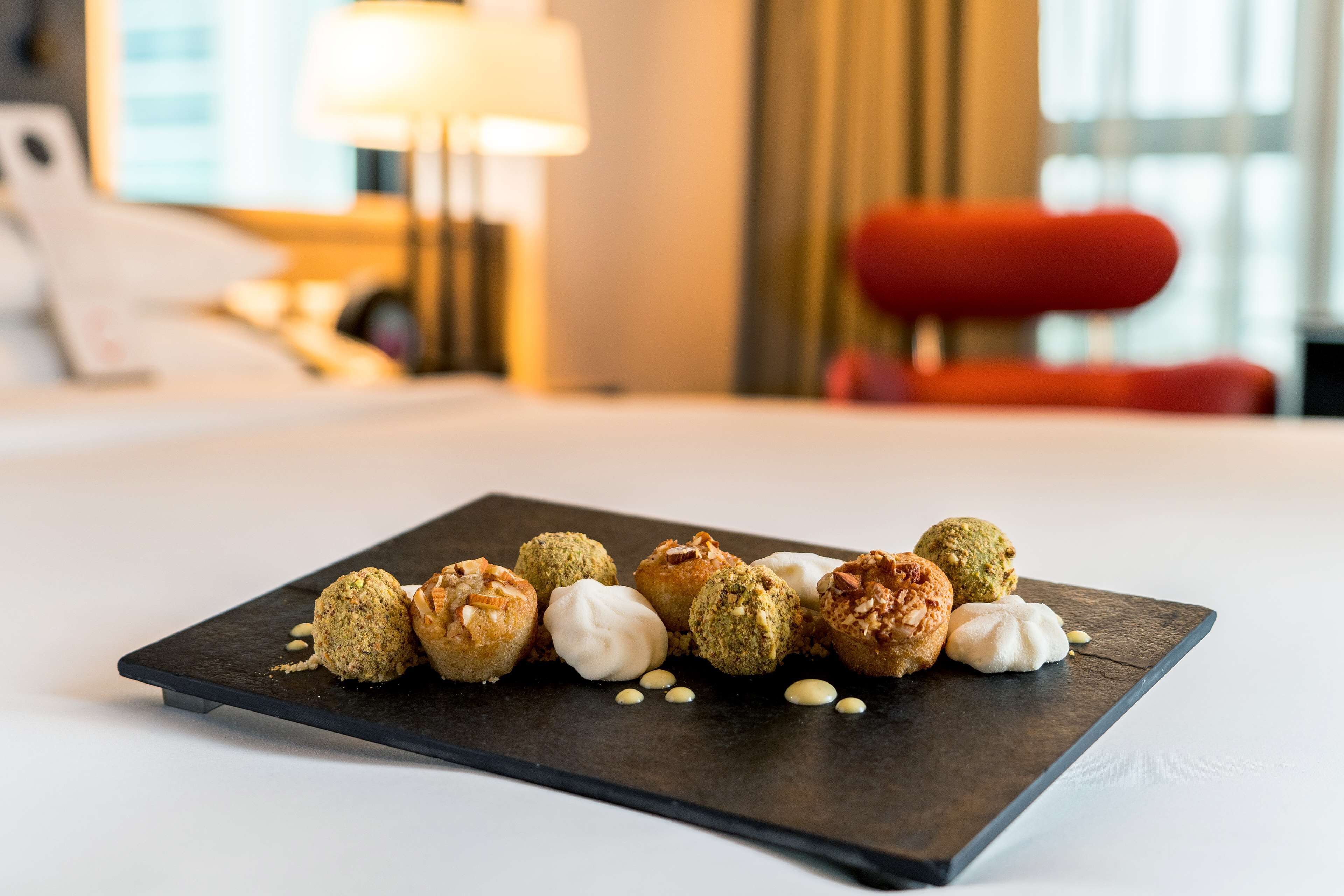 A dessert plate with various sweets on a slate board in a hotel room.