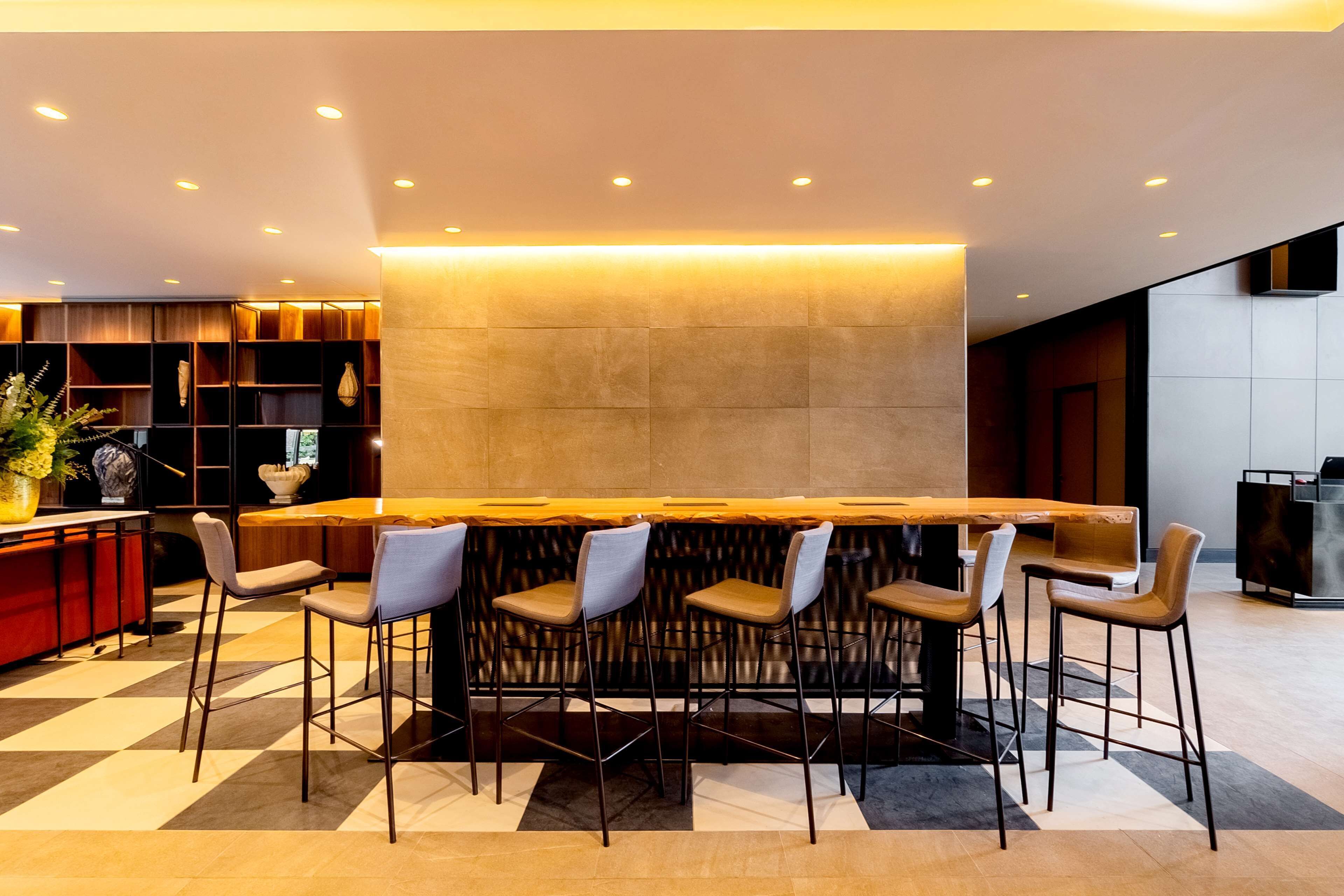 Een moderne bar met een lange houten tafel en zes barkrukken.