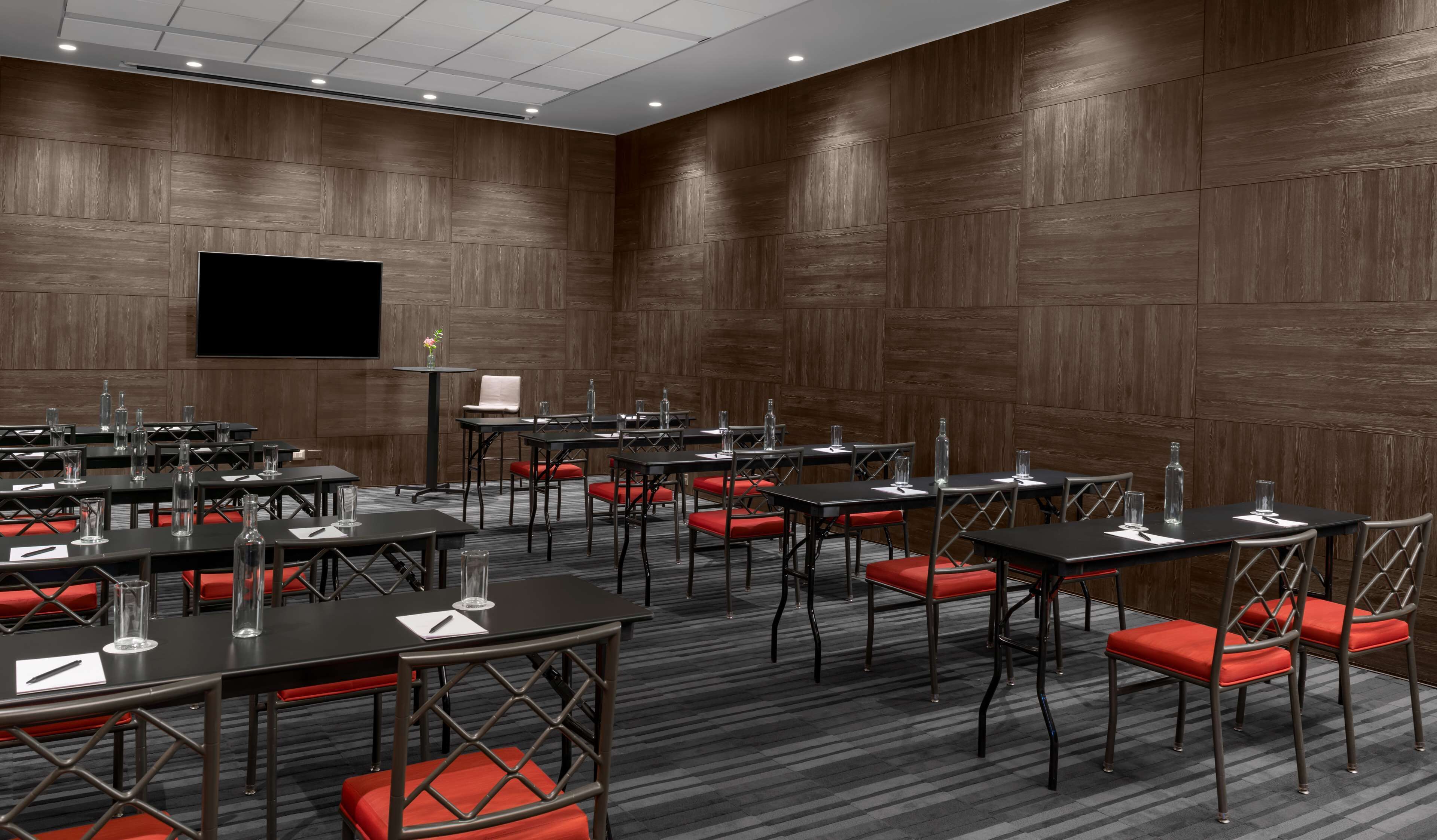 Une salle de conférence dotée de plusieurs tables et chaises, ainsi que de verres et de stylos.