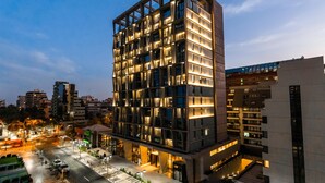 Un edificio moderno de varios pisos con fachada de diseño geométrico y ventanas iluminadas.