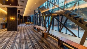 Un interior moderno con piso de madera, una escalera con barandillas de metal y ventanas amplias que dan vistas al exterior.