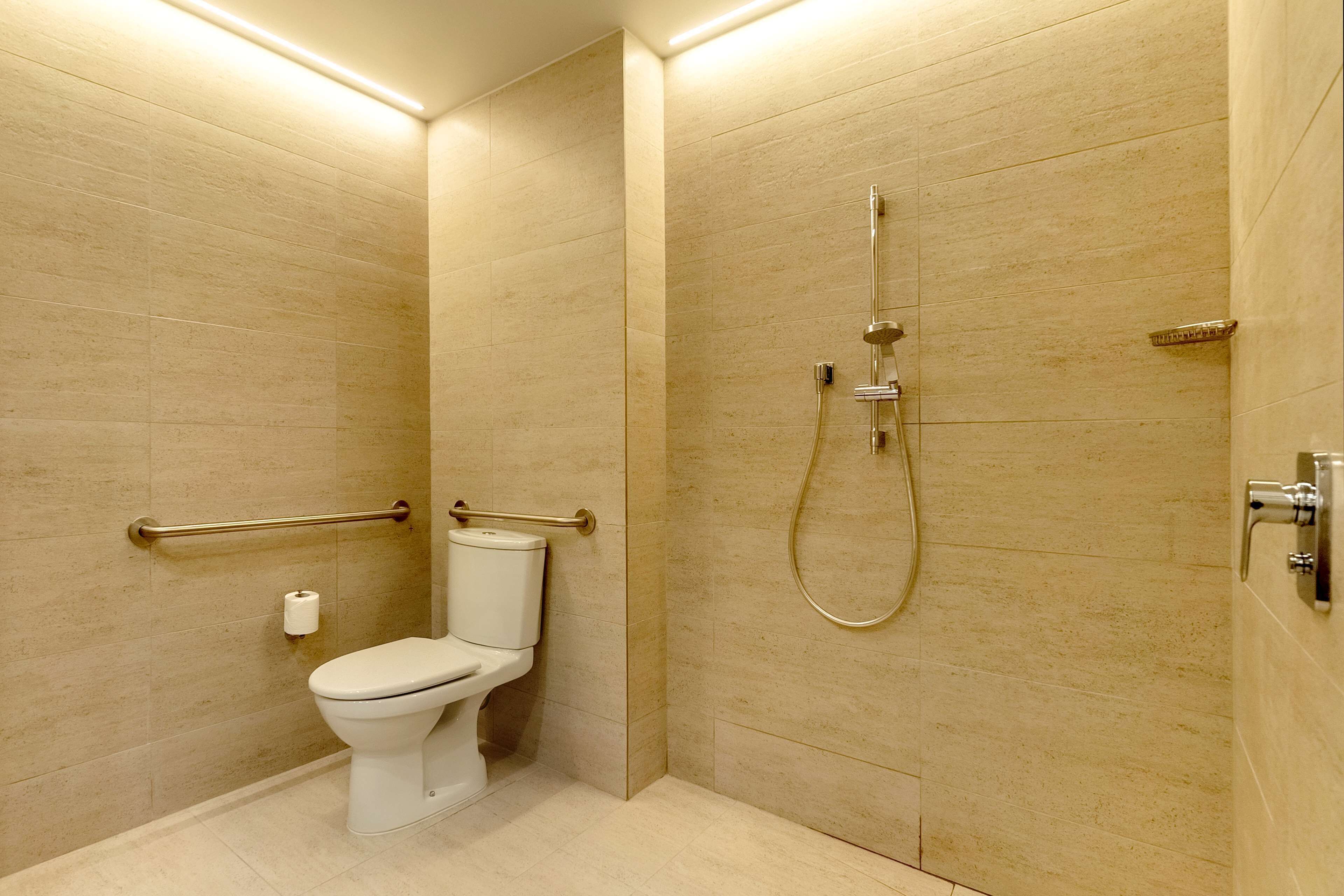 Un baño moderno con inodoro, ducha y barra de apoyo.