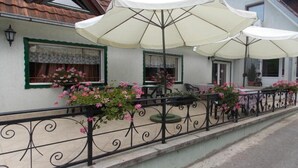 A building with outdoor seating, covered by umbrellas, and surrounded by a decorative fence.