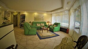A living room with green sofas, a coffee table, and a bookshelf.