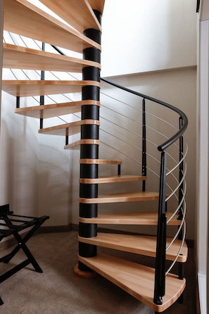 A spiral staircase with wooden steps and black railings.