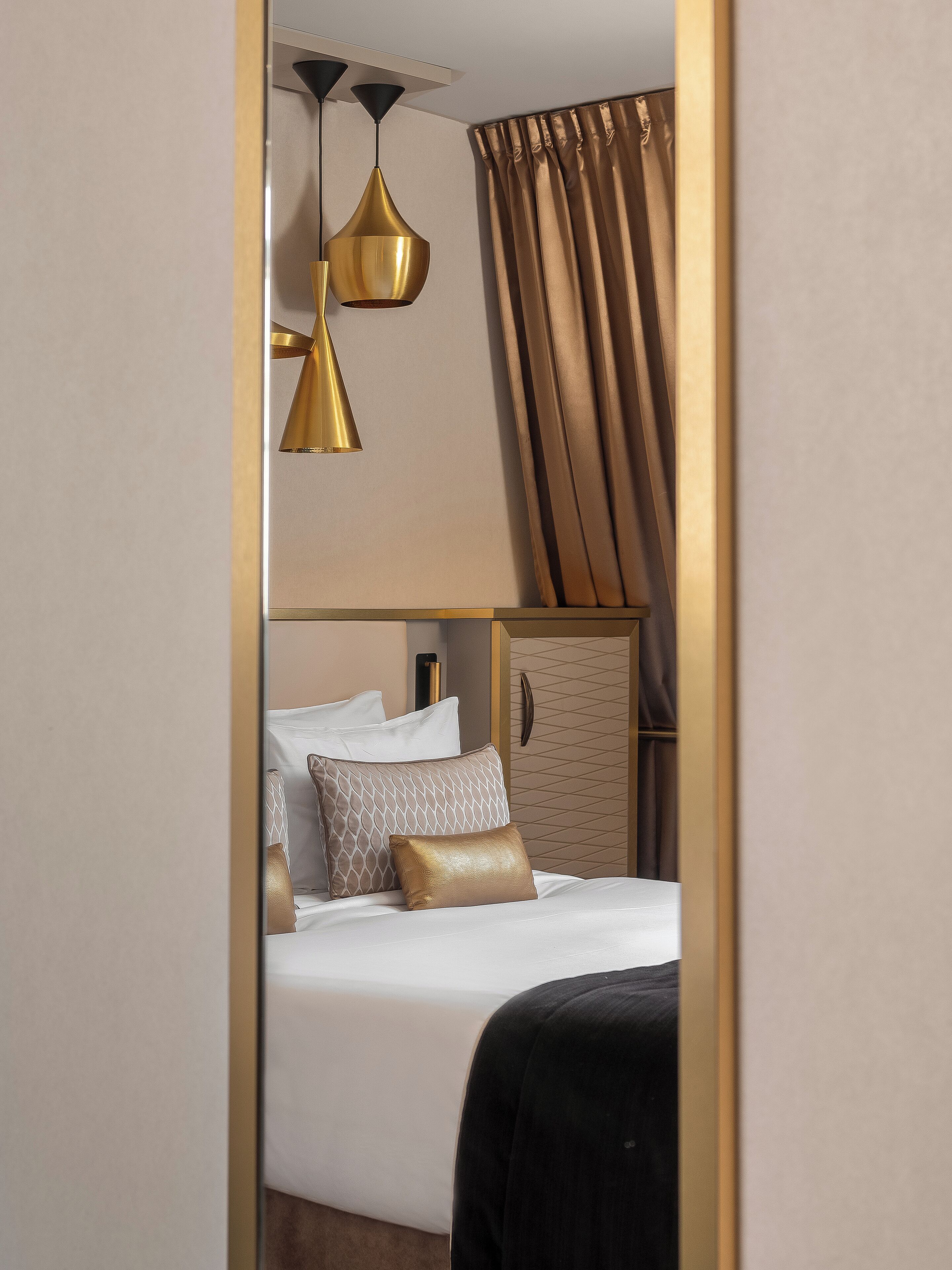 Habitación de hotel con cama, dos lámparas colgantes, un armario y una cortina.