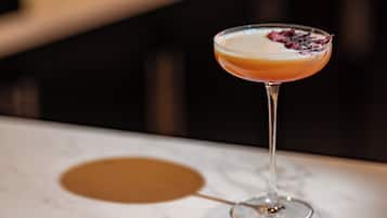 Un verre à martini contenant une boisson à plusieurs couches, posé sur une surface en marbre.