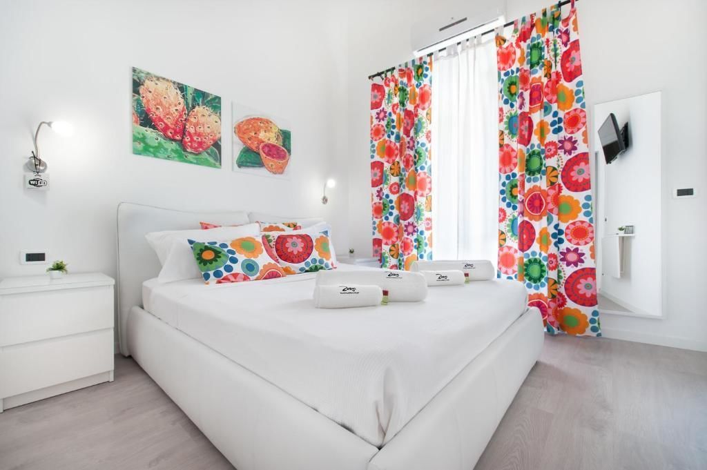 A modern bedroom with a white bed, colorful pillows, and a floral curtain.