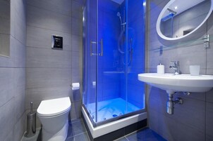 Un bagno moderno con doccia vetro, vaso bianco e lavandino con specchio.