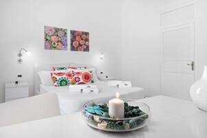 Una camera da letto moderna con un letto, comodini, abat-jour e una candela decorativa su un tavolino in vetro.