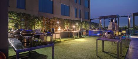 Un espace extérieur aménagé avec un barbecue, des tables et une pergola.