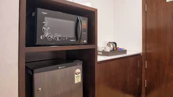 Une petite cuisine équipée d’un four à micro-ondes, d’un réfrigérateur et d’une étagère avec des bocaux.