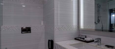Un baño moderno con un espejo grande, un inodoro blanco, un lavabo con encimera de mármol y una zona de ducha.