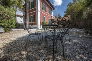 Relax in a serene outdoor space surrounded by lush greenery and a charming European-style building.