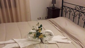 A neatly made bed with towels and a small bouquet of flowers. - Sciacca B&B Natoli (Sciacca)