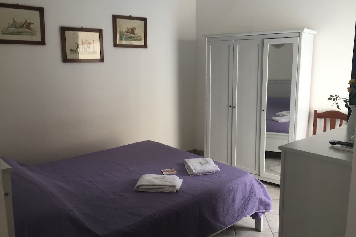 Une chambre à coucher avec un lit, une armoire et deux tableaux encadrés accrochés au mur.