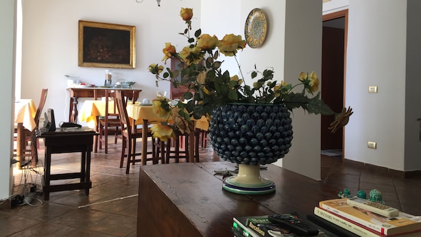 A dining area with a table set for two, a vase with yellow flowers, and a decorative lamp. - Sciacca B&B Natoli (Sciacca)