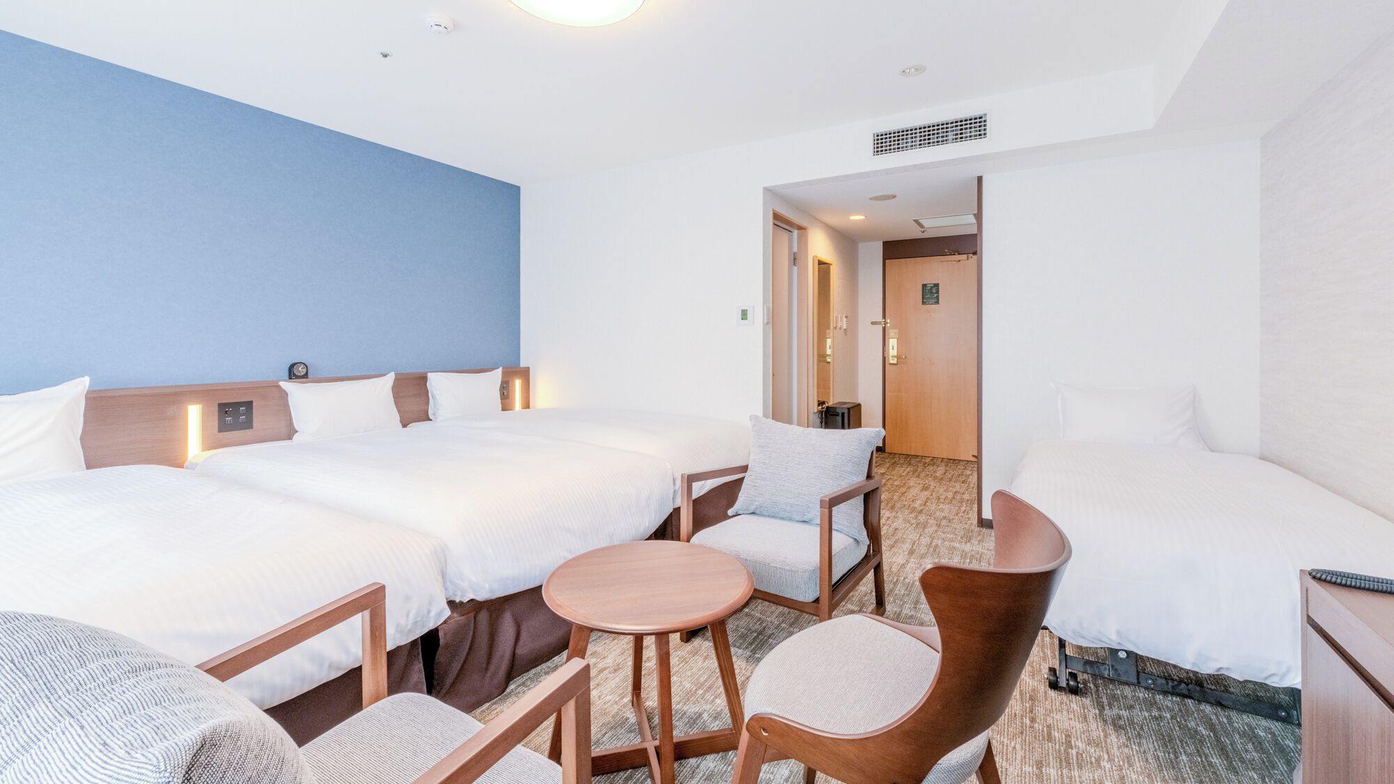 Une chambre d’hôtel avec deux lits, une petite table ronde et une chaise.
