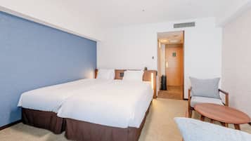 A hotel room with a large bed, a bedside table, a chair, and a small table.