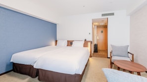 A hotel room with a large bed, a bedside table, a chair, and a small table.