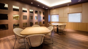A modern conference room with a large table and chairs, recessed lighting, and a patterned wall design.