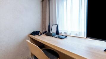 A hotel room with a wooden desk, a black bag, a smartphone, and a tablet.