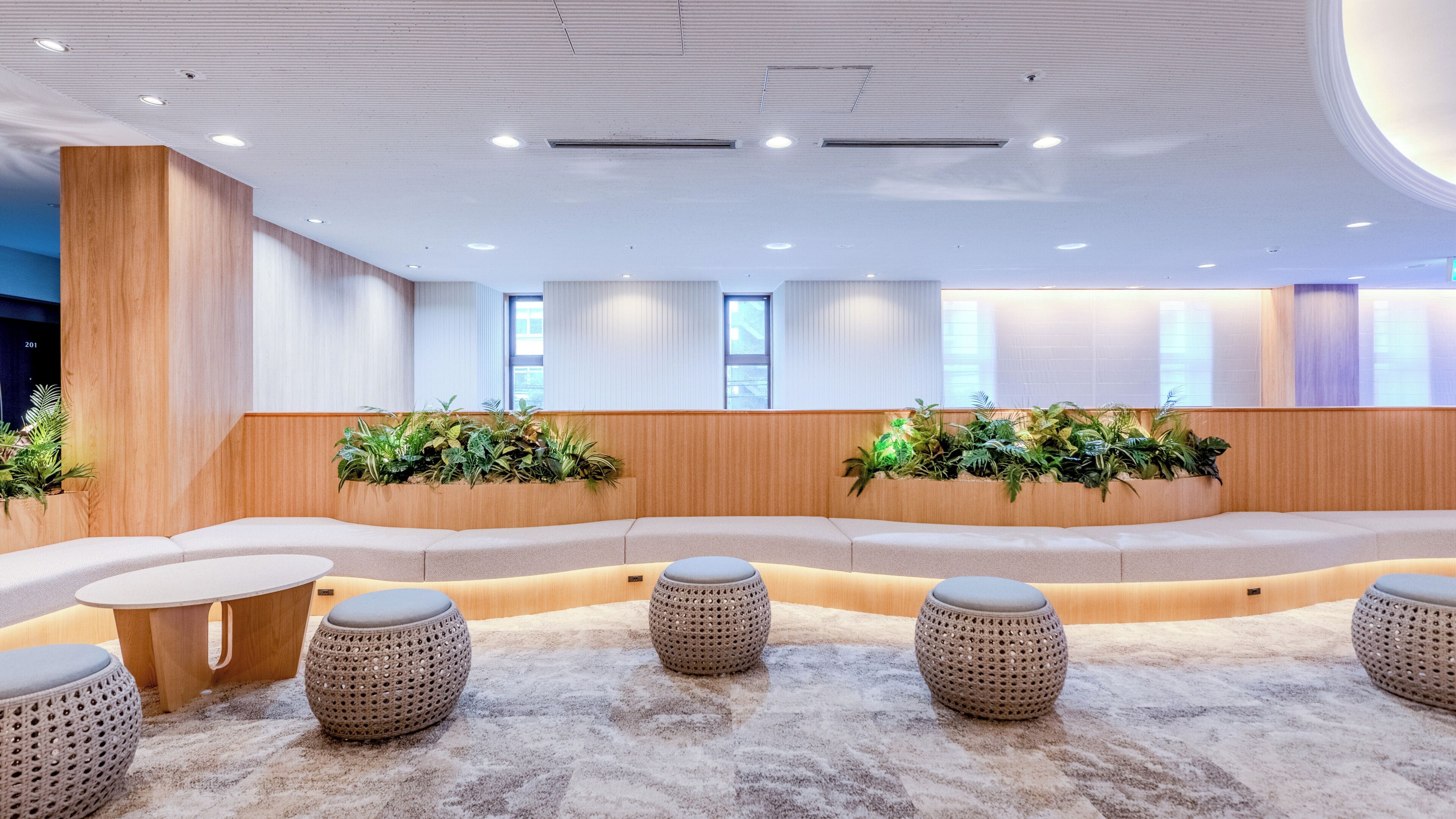 A modern interior with a curved seating area, round tables, and potted plants.