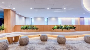 A modern interior with a curved seating area, round tables, and potted plants. - Richmond Hotel Naha Kumoji (Naha)