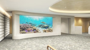 Un hall d’entrée moderne doté d’un grand écran numérique affichant une scène sous-marine, d’un comptoir d’accueil et d’un escalier.