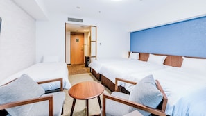 Habitación de hotel con dos camas, una mesita pequeña y dos sillas.