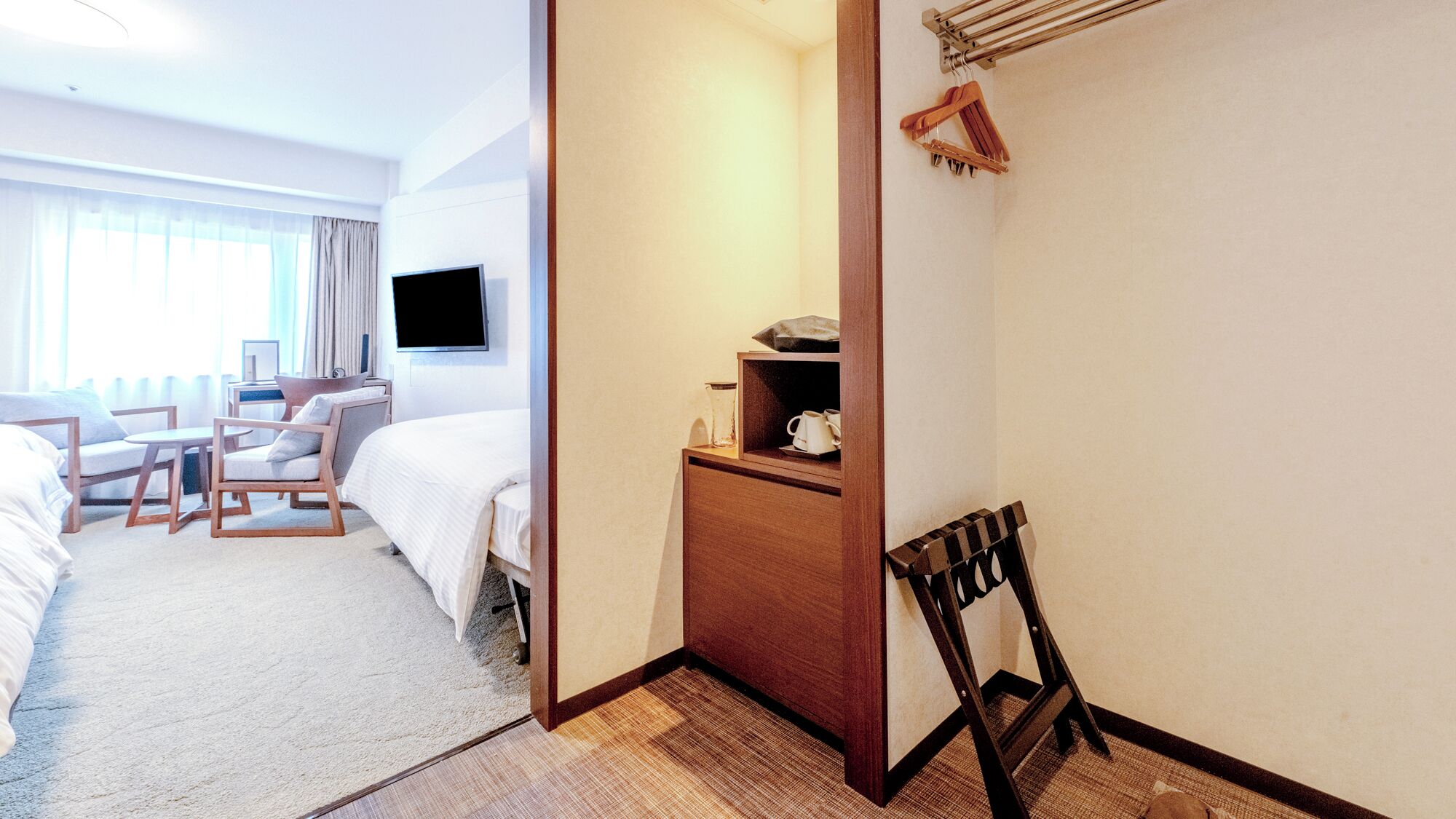 Een hotelkamer met een bed, een bureau, een stoel, een televisietoestel en een raam met gordijnen.
