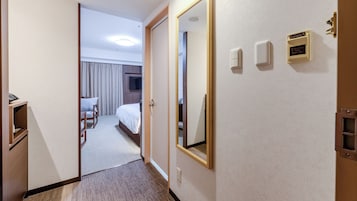 A hotel room with a bed, a desk, a chair, a television, and a mirror.