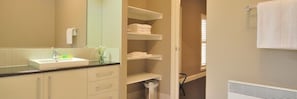 A bathroom with a sink, mirror, towel rack, and storage shelves. - Barkly Suites Apartments (Rutherglen)