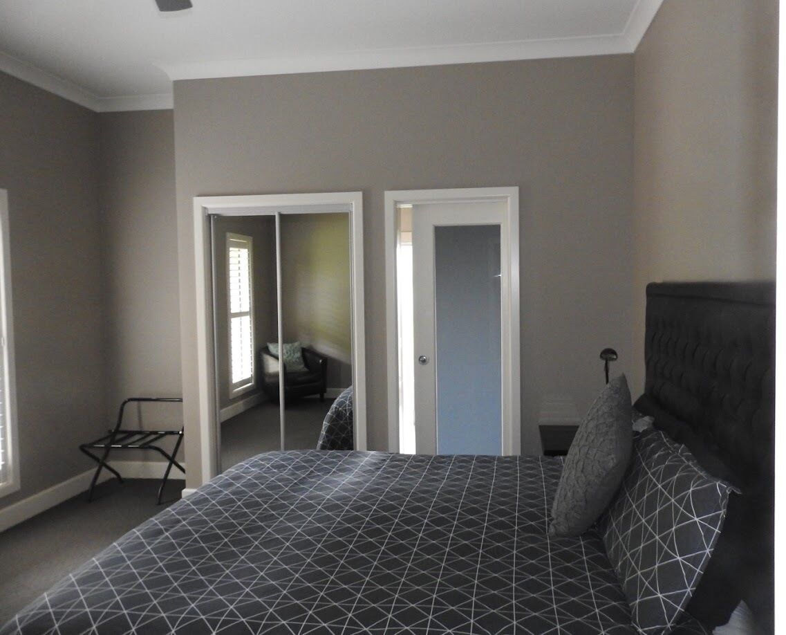A bedroom with a bed, a chair, and a door leading to another room.