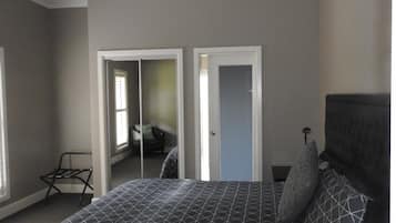 A bedroom with a bed, a chair, and a door leading to another room.