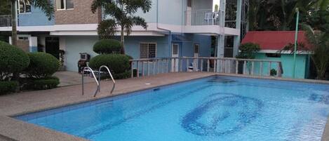 Alberca al aire libre, sombrillas en la alberca y camastros