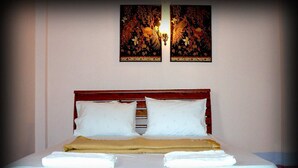 A neatly made bed with white linens and a brown blanket, a wooden headboard, and two wall-mounted artworks above. - D's Corner & Guesthouse (Phuket)
