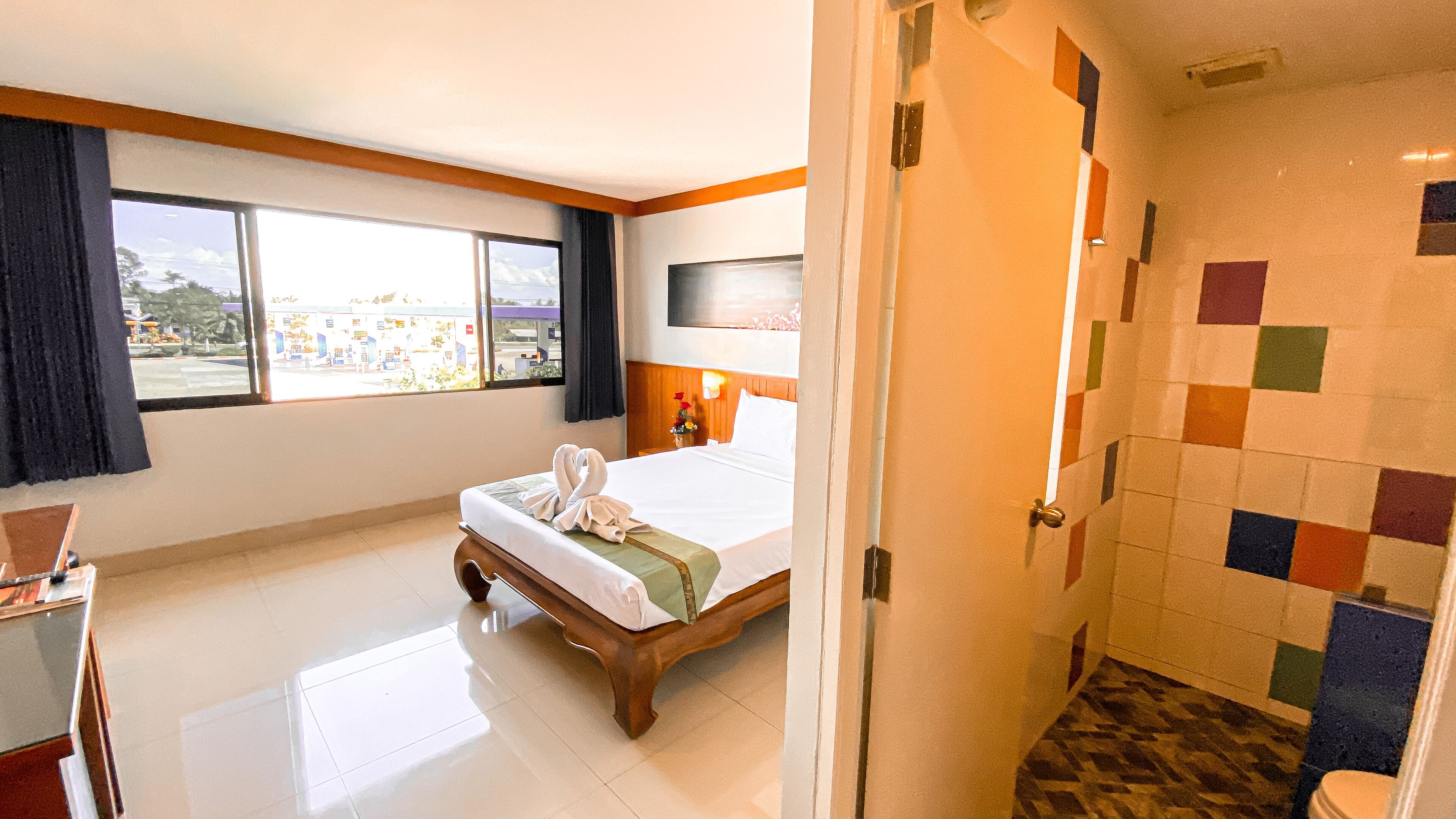 Quarto de hotel com cama, escrivaninha, televisão e banheiro.