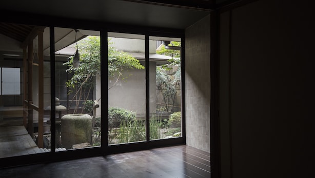 A traditional Japanese room with tatami flooring, sliding doors, and a view of a garden with a stone lantern and greenery. - KYOTO Yadomachi Nishijin (Kyoto)