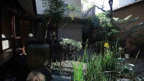 A traditional Japanese garden with stone lanterns, a small tree, and a gravel path. - KYOTO Yadomachi Nishijin (Kyoto)