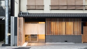 A building with a traditional Japanese entrance, wooden slats, and a modern facade. - KYOTO Yadomachi Nishijin (Kyoto)
