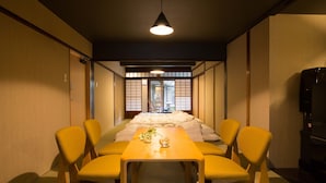 A traditional Japanese-style room with tatami flooring, a low table with cushions, and a sliding door leading to a bathroom. - KYOTO Yadomachi Nishijin (Kyoto)