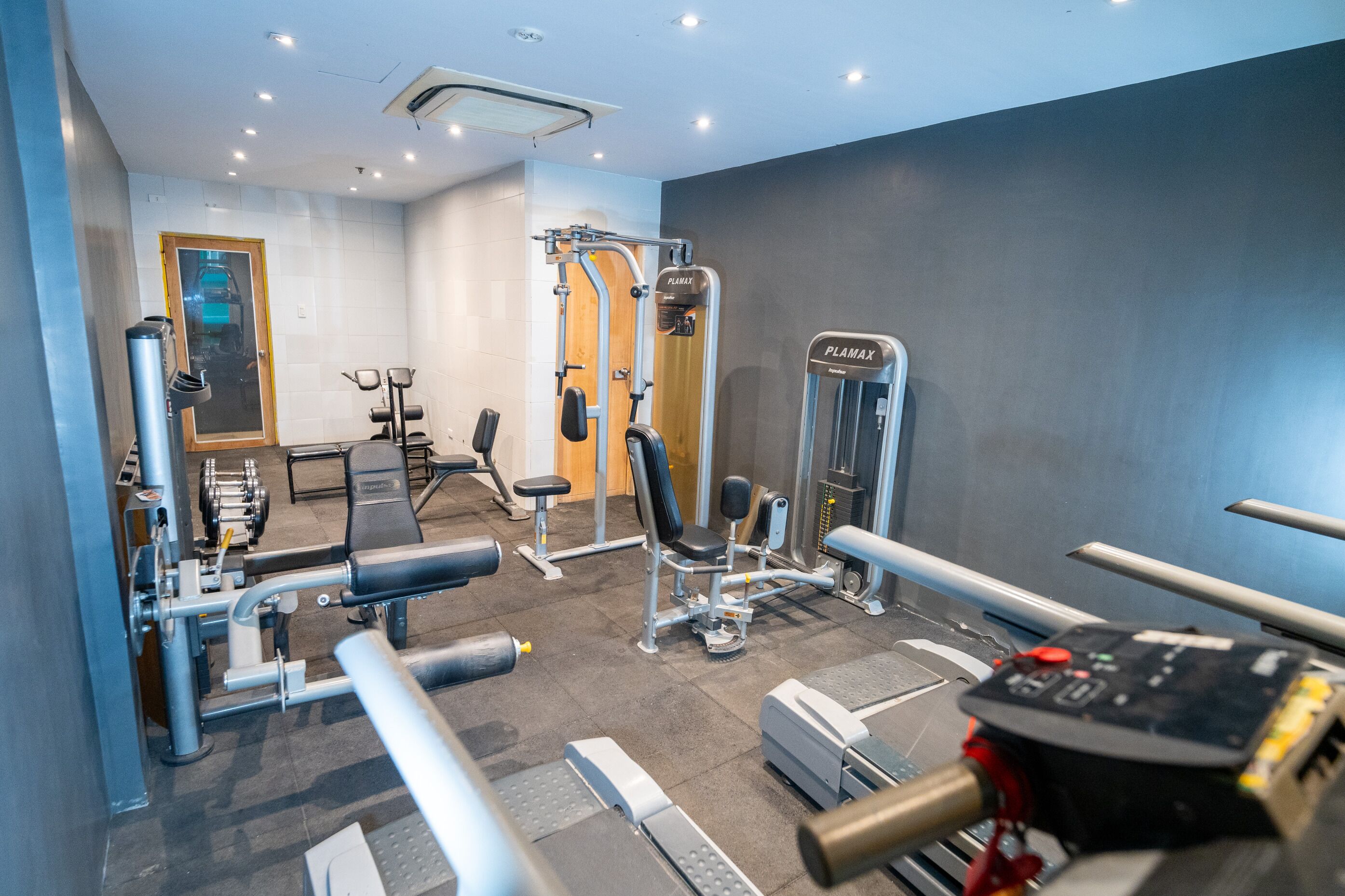 A modern gym with various exercise equipment, including a bench press, leg press, and a treadmill.