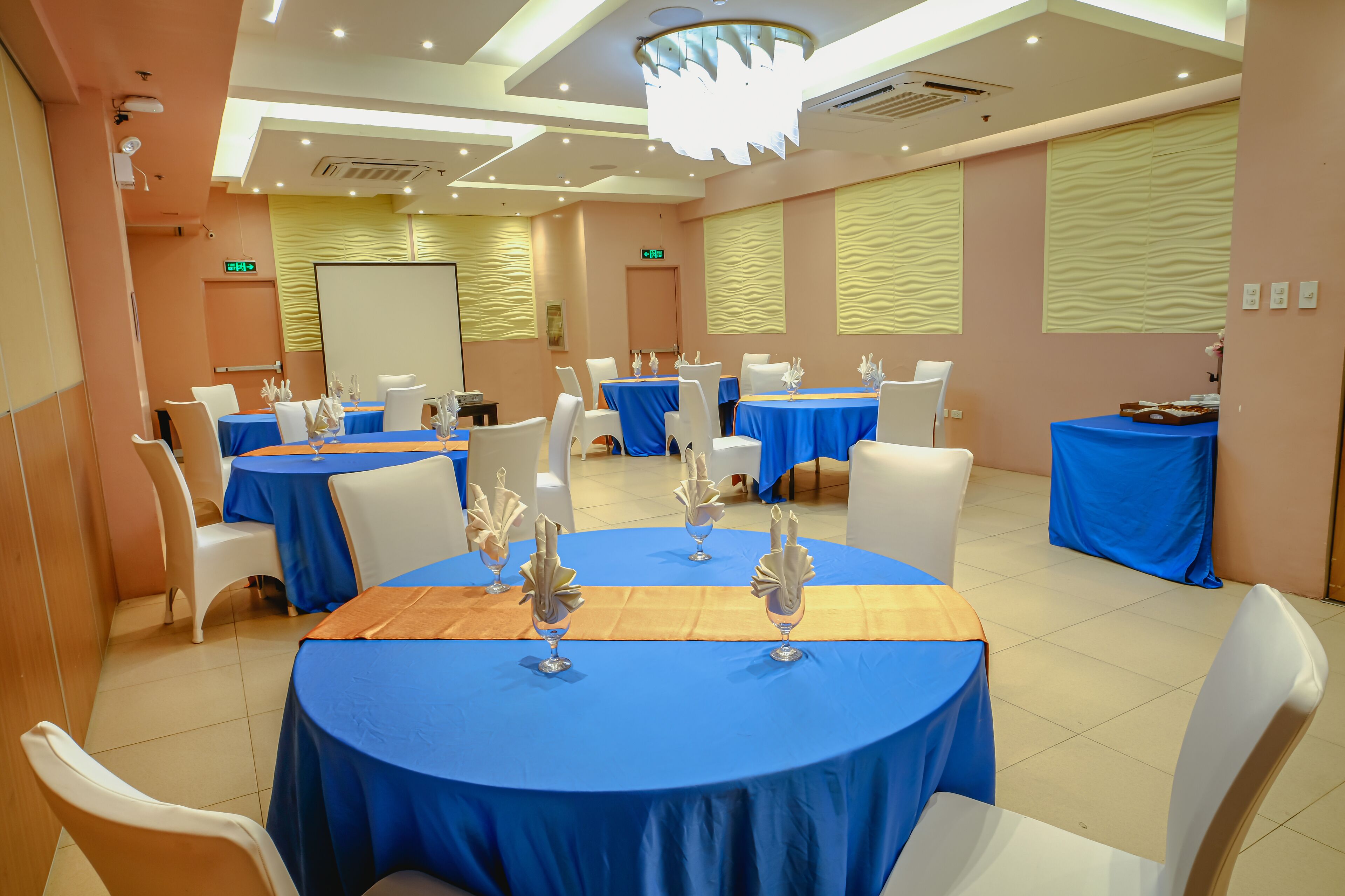 A conference room with round tables, white chairs, and blue tablecloths.