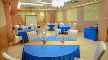 A conference room with round tables, white chairs, and blue tablecloths.